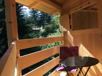 Cabane en bois avec balcon, offrant une vue sur la nature verdoyante en Auvergne.