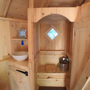 Cabane en bois chaleureuse avec un lavabo et une fenêtre en forme de diamant.