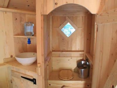 Cabane en bois chaleureuse avec un lavabo et une fenêtre en forme de diamant.