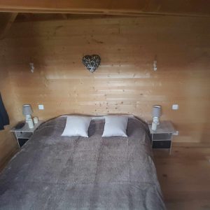 Chalet en bois chaleureux avec lit douillet et décor en bois naturel.