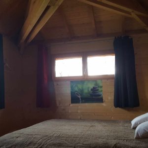 Chalet en bois cosy en Aquitaine, avec lit douillet et fenêtres lumineuses.