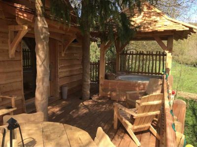 Cabane en bois avec terrasse et jacuzzi, entourée de verdure en Île-de-France.