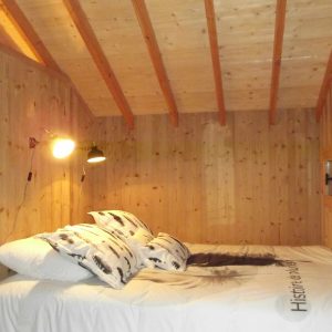 Cabane en bois cosy avec un lit douillet et des murs en bois chaleureux.