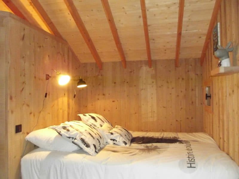 Chalet en bois chaleureux avec un lit douillet et des murs en bois clair.