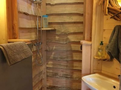 Douche en bois dans un hébergement insolite en Île-de-France, ambiance chaleureuse.