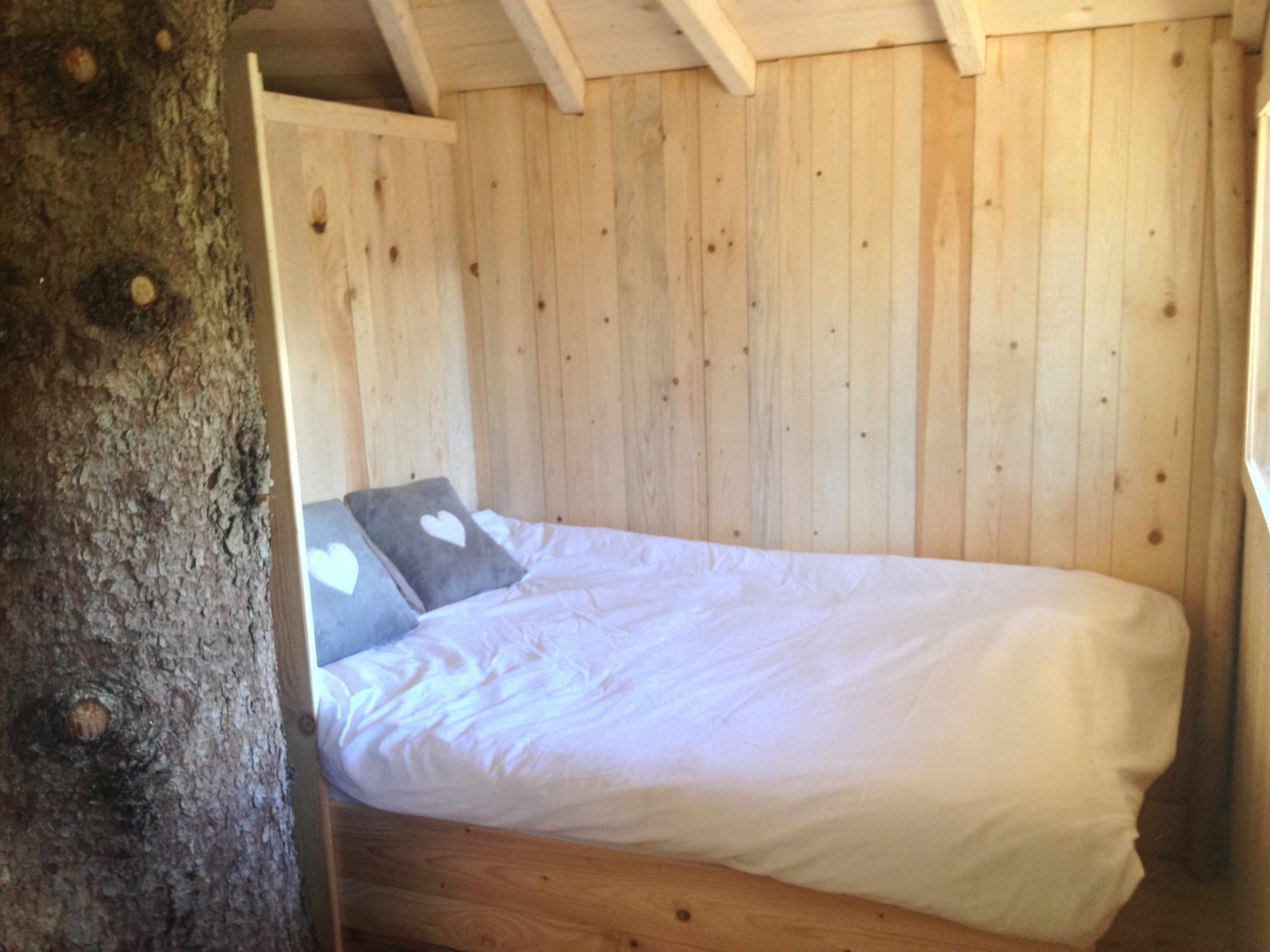 IMG_2034 Cabane en bois dans les arbres, lit douillet avec coussins en forme de cœur.