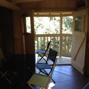 Cabane en bois avec balcon, offrant une vue sur la forêt en Auvergne-Rhône-Alpes.