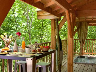Cabane dans les arbres à Limousin, avec terrasse en bois et vue sur la nature verdoyante.