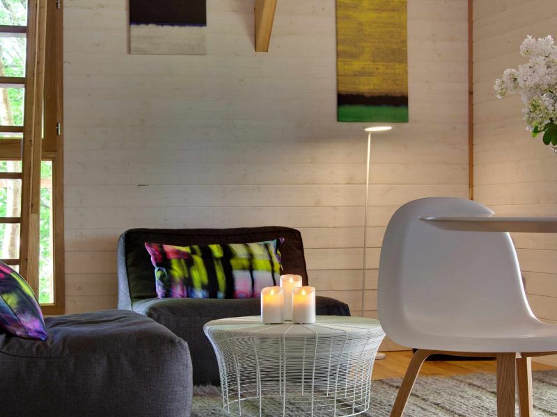 Chalet moderne avec un salon lumineux, décoré de tableaux colorés et de bougies.