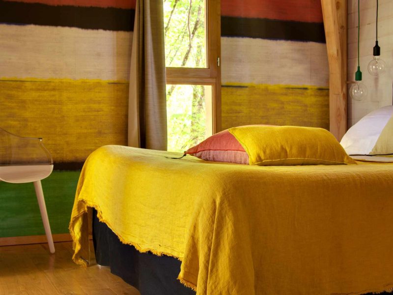 Chalet moderne avec un lit aux draps jaunes et des murs colorés.
