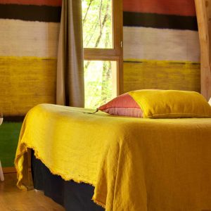 Chalet coloré à Limousin avec un lit aux draps jaunes et des murs artistiques.