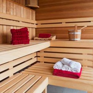 Sauna en bois chaleureux avec serviettes rouges, idéal pour une détente unique.
