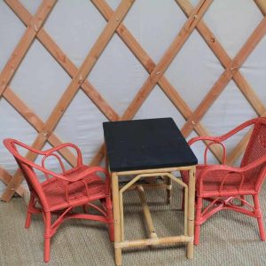 Yourte cosy au Centre, avec table noire et chaises en rotin rouge.