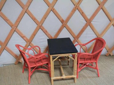 Yourte cosy au Centre, avec table noire et chaises en rotin rouge.
