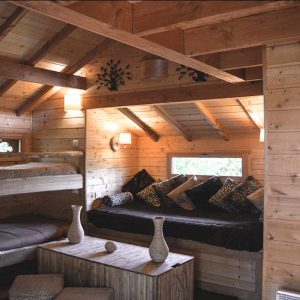Cabane en bois avec intérieur chaleureux, lits superposés et coin salon cosy.