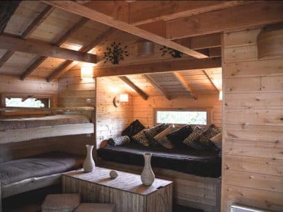 Cabane en bois avec intérieur chaleureux, lits superposés et coin salon cosy.
