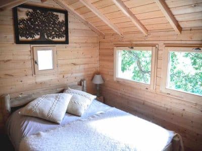 Cabane en bois à Ile-de-France, avec lit douillet et fenêtres sur la nature.