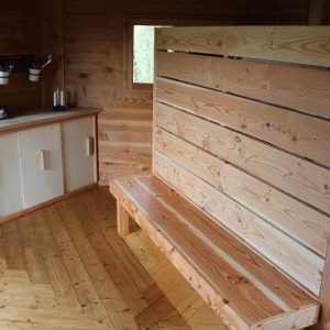 Hébergement insolite en bois avec un coin salon et kitchenette, ambiance chaleureuse.