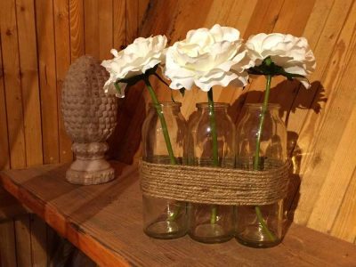 Hébergement insolite en Bourgogne avec des fleurs blanches dans des bouteilles en verre.