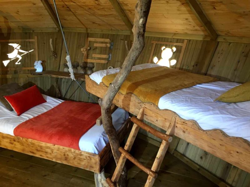 Cabane en bois avec lits superposés, décor chaleureux et touches naturelles.