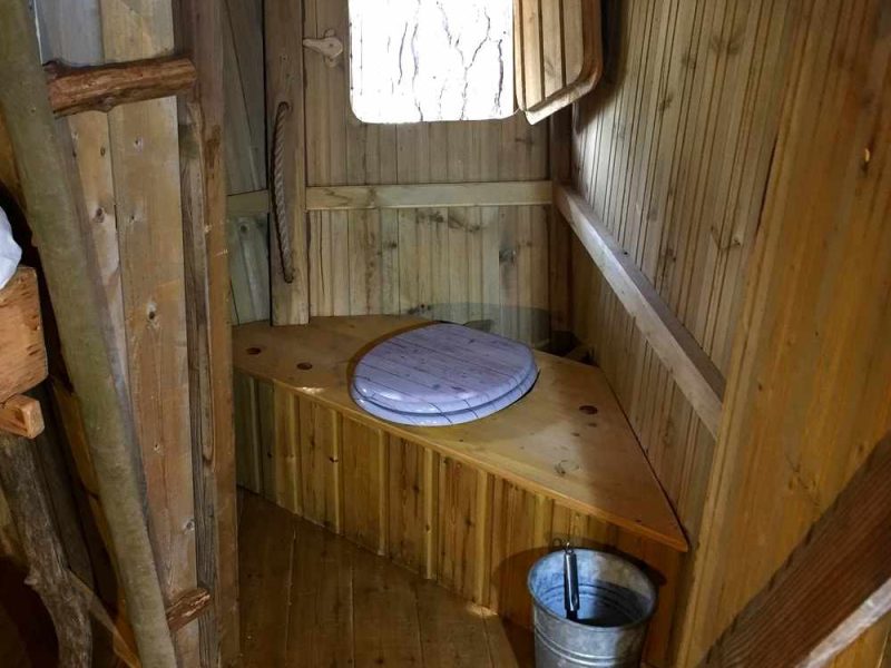 Cabane en bois avec toilettes écologiques et vue sur la nature.
