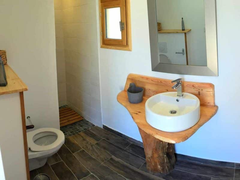 Salle de bain moderne dans un hébergement écologique, avec lavabo en bois naturel.