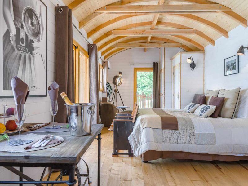 Chalet en bois avec plafond en poutres, décor cosy et vue sur la nature.
