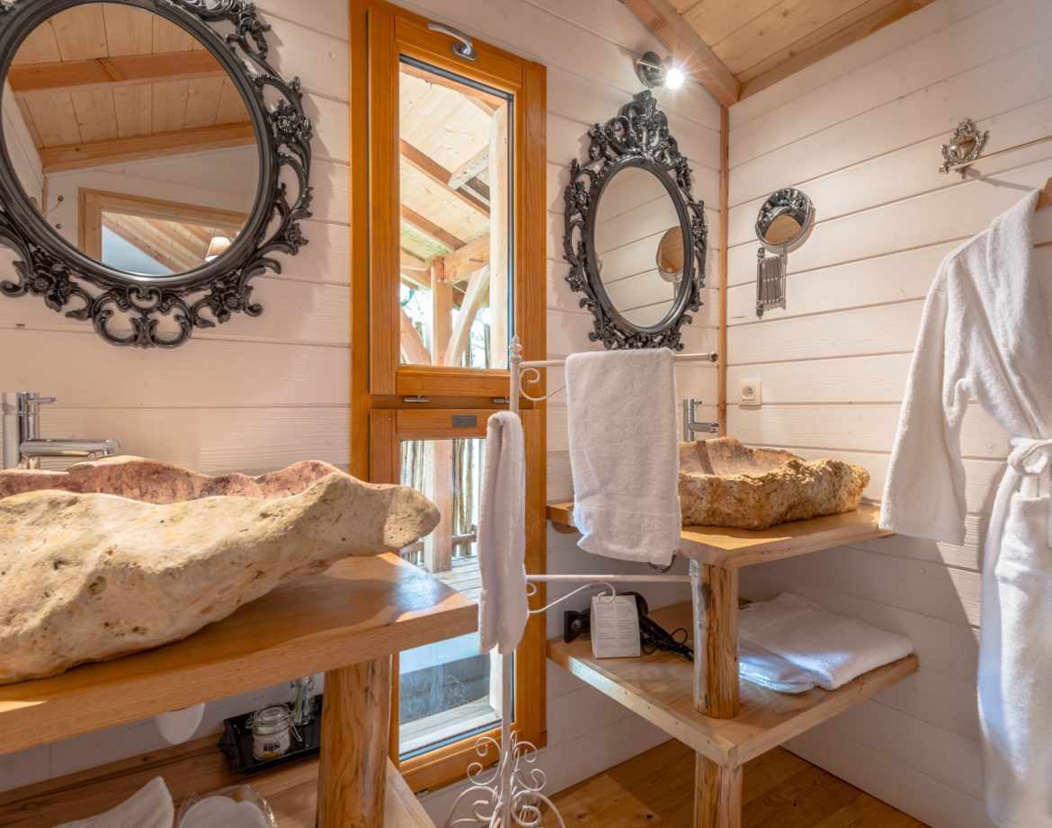 Salle de bain dun hébergement insolite en Aquitaine avec lavabos en bois naturel.