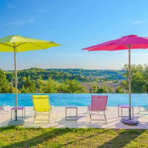 Hébergement insolite en Aquitaine avec piscine à débordement et parasols colorés.