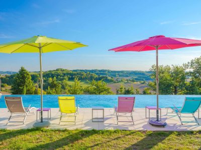 Hébergement insolite en Aquitaine avec piscine à débordement et parasols colorés.