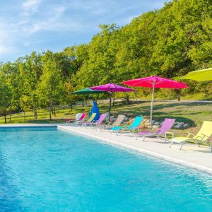 Hébergement insolite en Aquitaine avec piscine et transats colorés sous des parasols.