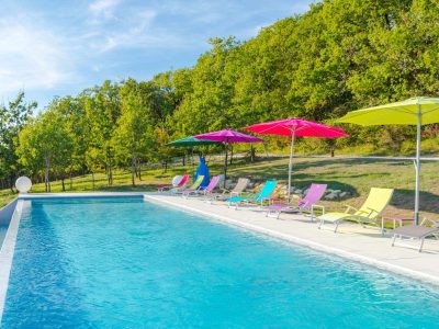Hébergement insolite en Aquitaine avec piscine et transats colorés sous des parasols.