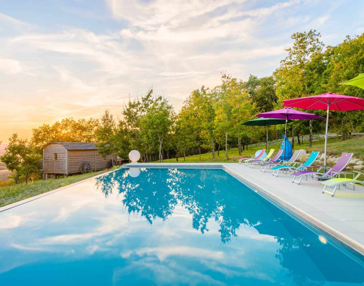 Hébergement insolite en Aquitaine avec piscine et transats colorés au coucher de soleil.