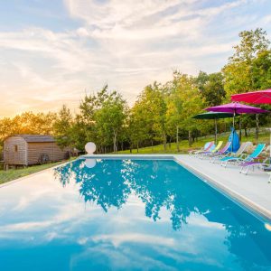 Hébergement insolite en Aquitaine avec piscine et transats colorés au coucher de soleil.