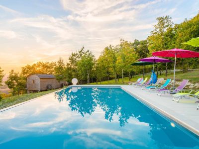 Hébergement insolite en Aquitaine avec piscine et transats colorés au coucher de soleil.