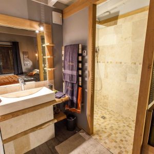 Salle de bain moderne dun hébergement insolite en Aquitaine, avec douche en pierre.