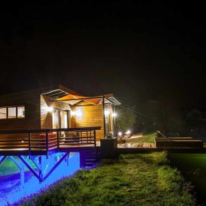 Cabane sur pilotis en Aquitaine, illuminée au bord de leau la nuit.