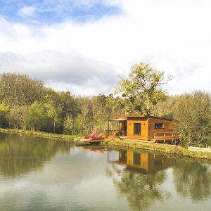 Cabane en bois au bord dun lac, entourée de verdure en Aquitaine.
