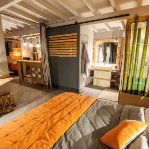 Hébergement insolite en Aquitaine : chambre moderne avec lit orange et décor en bois.