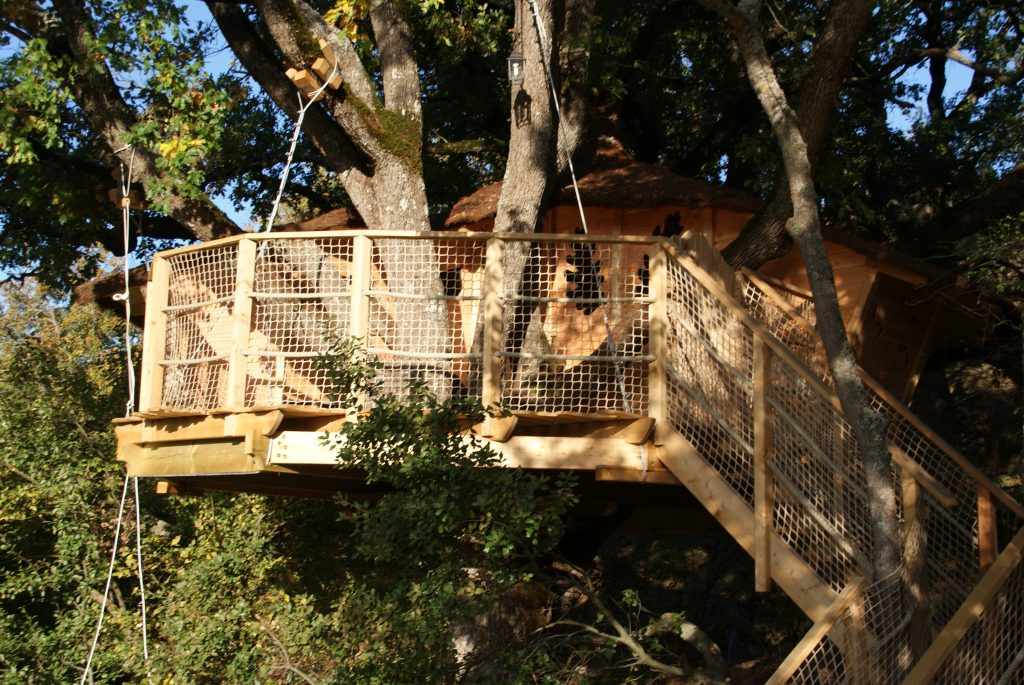 Cabane perchée dans les arbres, en bois, entourée de verdure à Provence-Alpes-Côte dAzur.