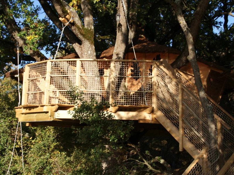 Cabane perchée dans les arbres, en bois, entourée de verdure à Provence-Alpes-Côte dAzur.