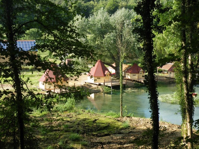 Hébergement insolite en cabanes au bord dun lac, entouré de verdure luxuriante.
