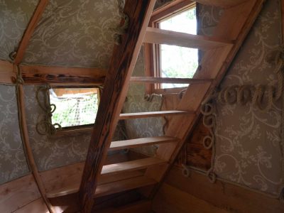 Cabane perchée en Midi-Pyrénées avec un escalier en bois et des murs décorés.