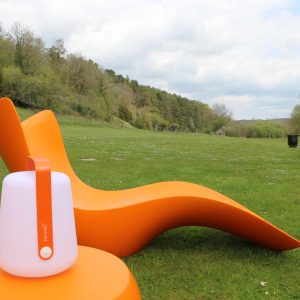 Hébergement insolite en Bourgogne avec des chaises longues orange sur un vaste terrain verdoyant.