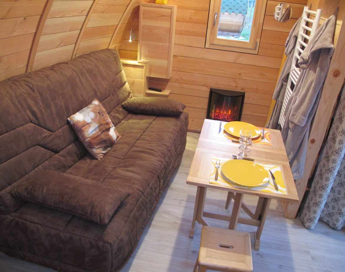 Hébergement insolite en bois à Champagne-Ardenne, avec un coin salon cosy et cheminée.