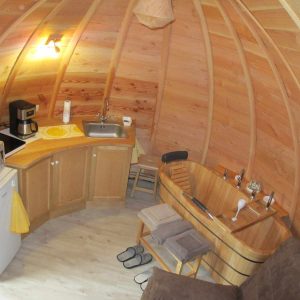 Hébergement insolite en forme de bulle avec intérieur en bois et baignoire en bois.