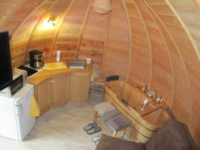 Hébergement insolite en forme de bulle avec intérieur en bois et baignoire en bois.