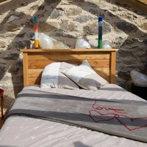 Chalet en pierre avec lit douillet et décor coloré, idéal pour un séjour unique.