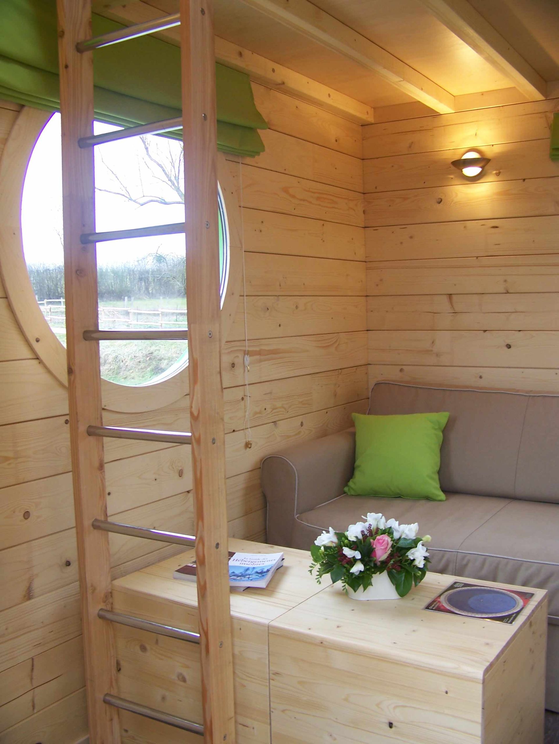 100_0886 Hébergement insolite en bois avec un coin salon et une fenêtre ronde.