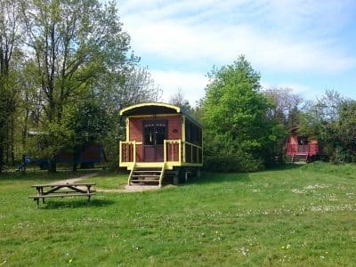 Hébergement insolite : une roulotte colorée entourée de verdure et darbres.